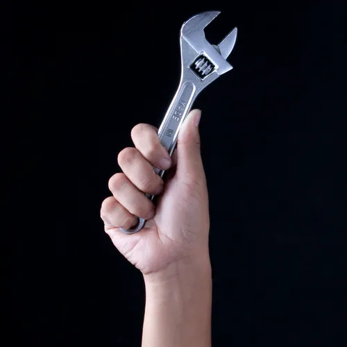 A hand holding a wrench — a tool built by the people who needed it